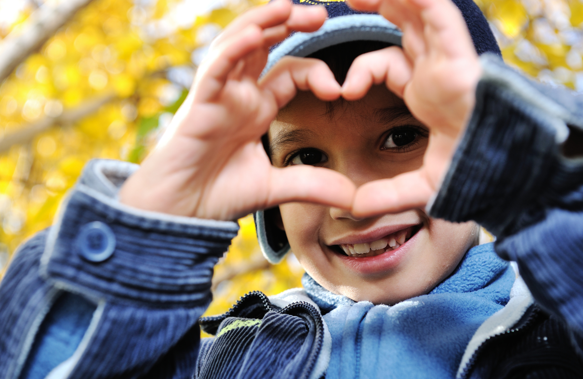 Childing holding up their hands in the shape of a heart.