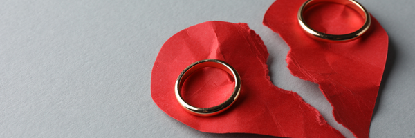 Red Paper heart crumpled and torn in half with a wedding ring on each side.