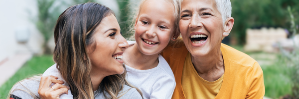 Three generations of women laughing together outdoors