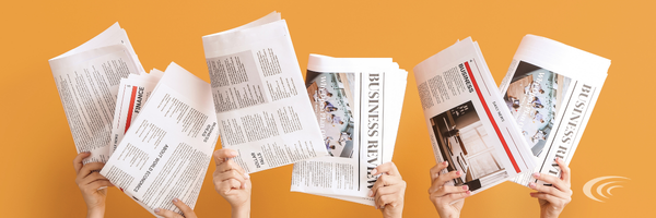 Several hands holding up business newspapers against an orange background.